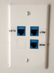 Jack jumper ppanel on wall with three ports. Top Left says Data, Top Right sys LRM, Bottom Right says BRM